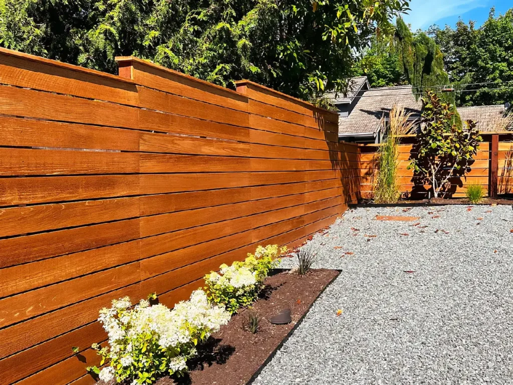 Stained wood fence providing a modern look in a gravel backyard, enhancing the outdoor space with a beautiful new fence.