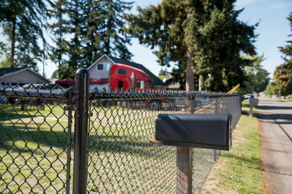 Chain link fence along a residential property with sidewalk view.