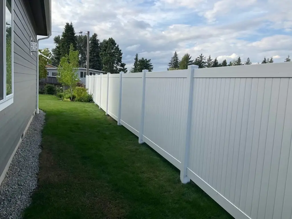A vinyl fence running along a well-maintained lawn, highlighting the durability of vinyl in comparison to cedar vs vinyl fences.A vinyl fence running along a well-maintained lawn, highlighting the durability of vinyl in comparison to cedar vs vinyl fences.