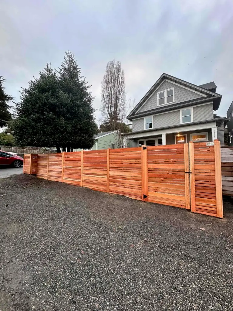 Traditional cedar fence with horizontal planks in Seattle, designed to blend seamlessly with natural surroundings.