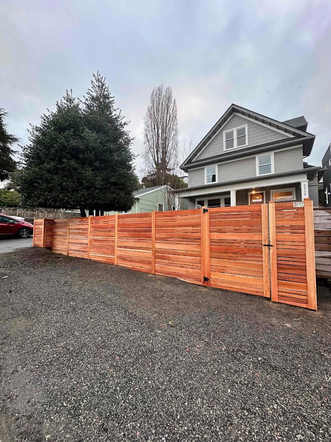 A contemporary horizontal cedar fence installed in a clean, green yard, demonstrating the natural and rustic appeal of cedar vs vinyl fences.