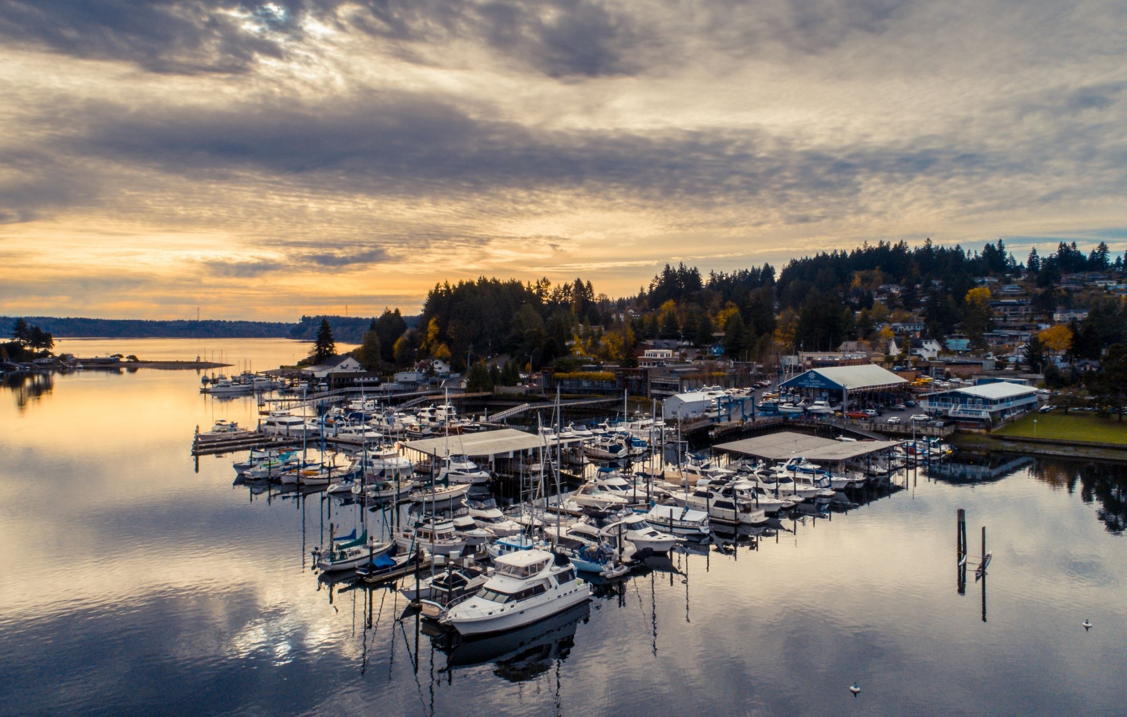 Aerial view of Gig Harbor, FL marina at sunset with boats and waterfront buildings.