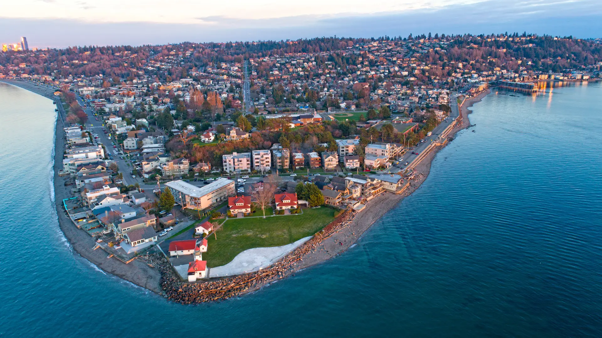 Alki WA coastal area with a lighthouse, beach, and city skyline.