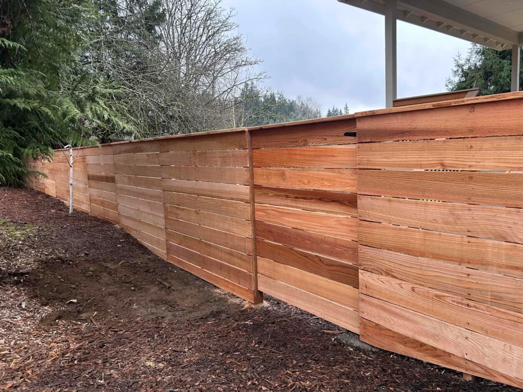 A newly installed modern horizontal cedar fence on a sloped yard, demonstrating thoughtful Horizontal fence height rules.