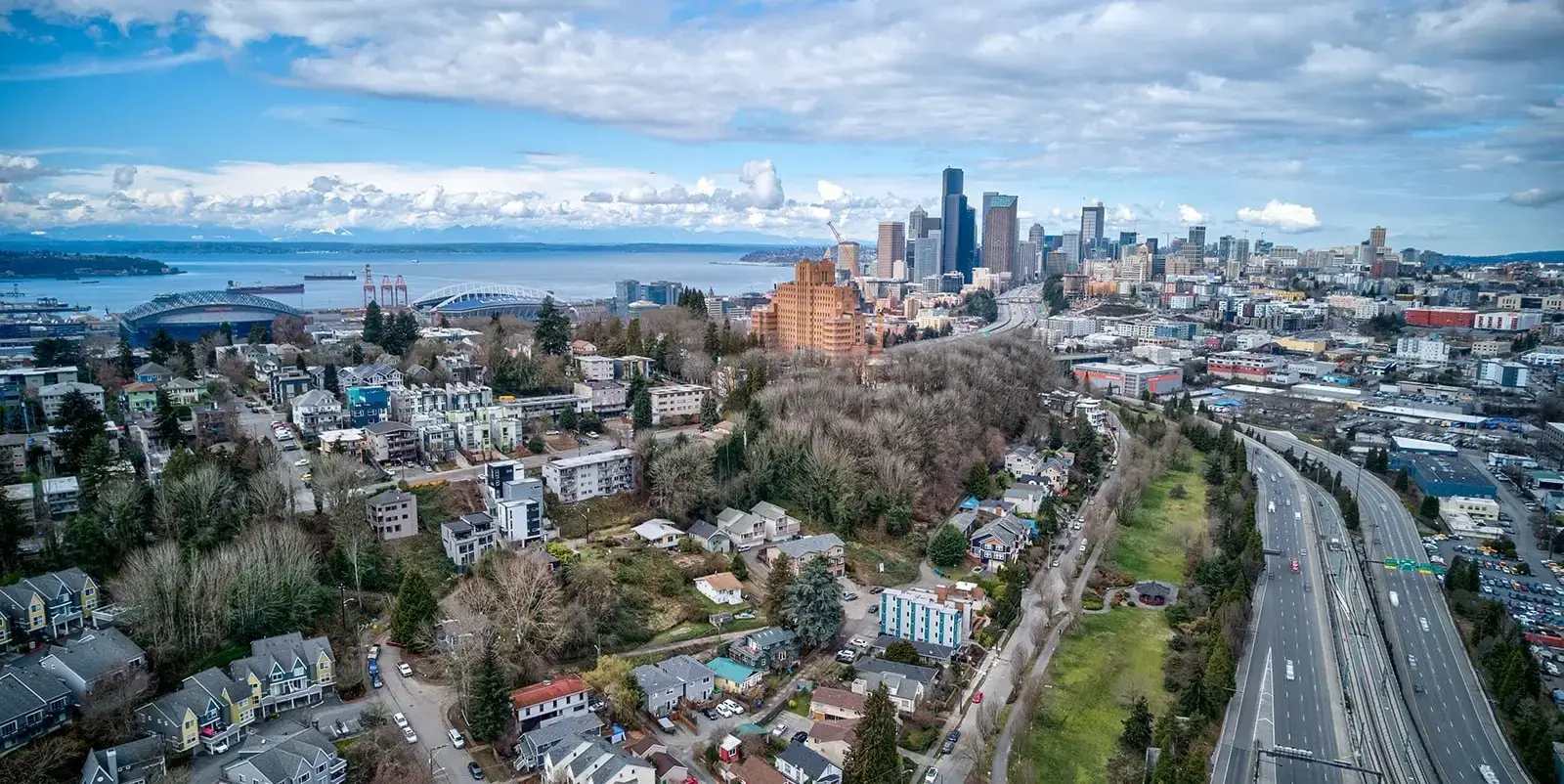 Aerial view of Beacon Hill, WA, with homes, I-5, and Seattle skyline.