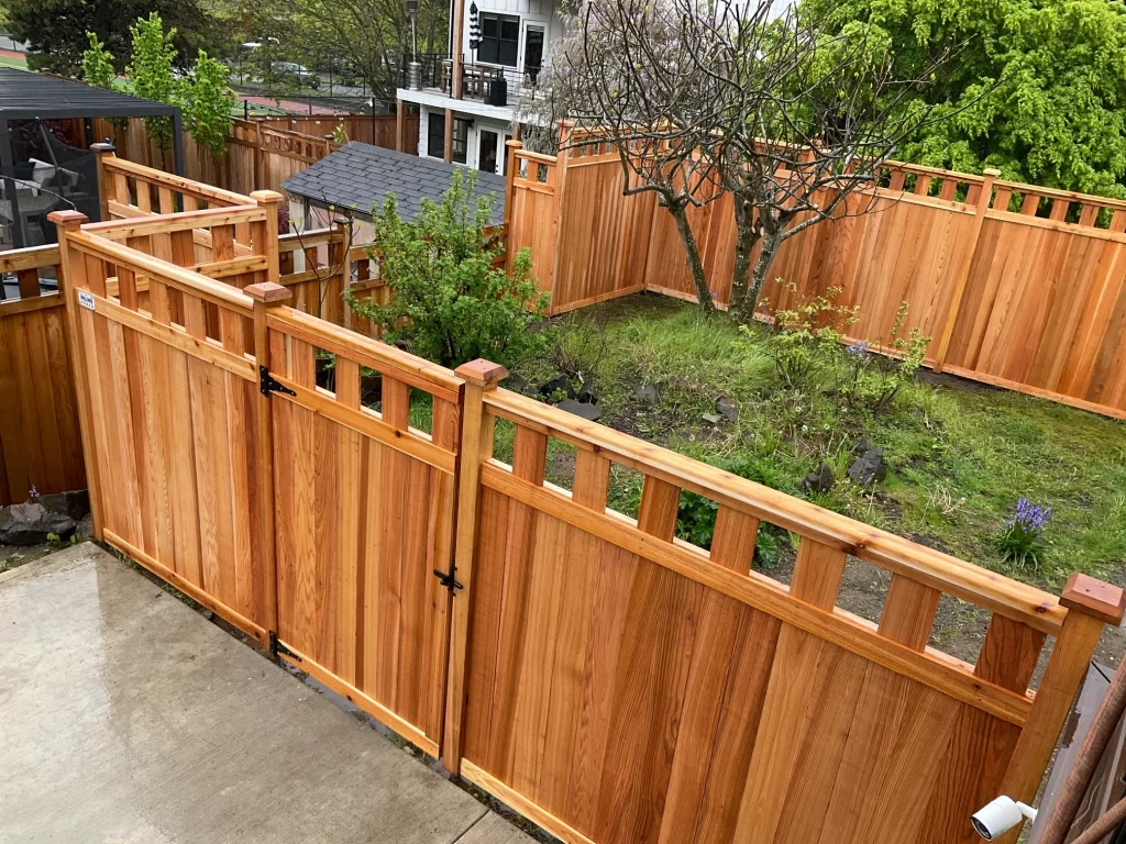 New cedar wooden privacy fence with a secure black gate and custom top rail design.