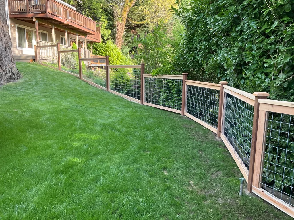 A curved hog wire fence on a sloped yard, offering security and aesthetic appeal for residential properties.