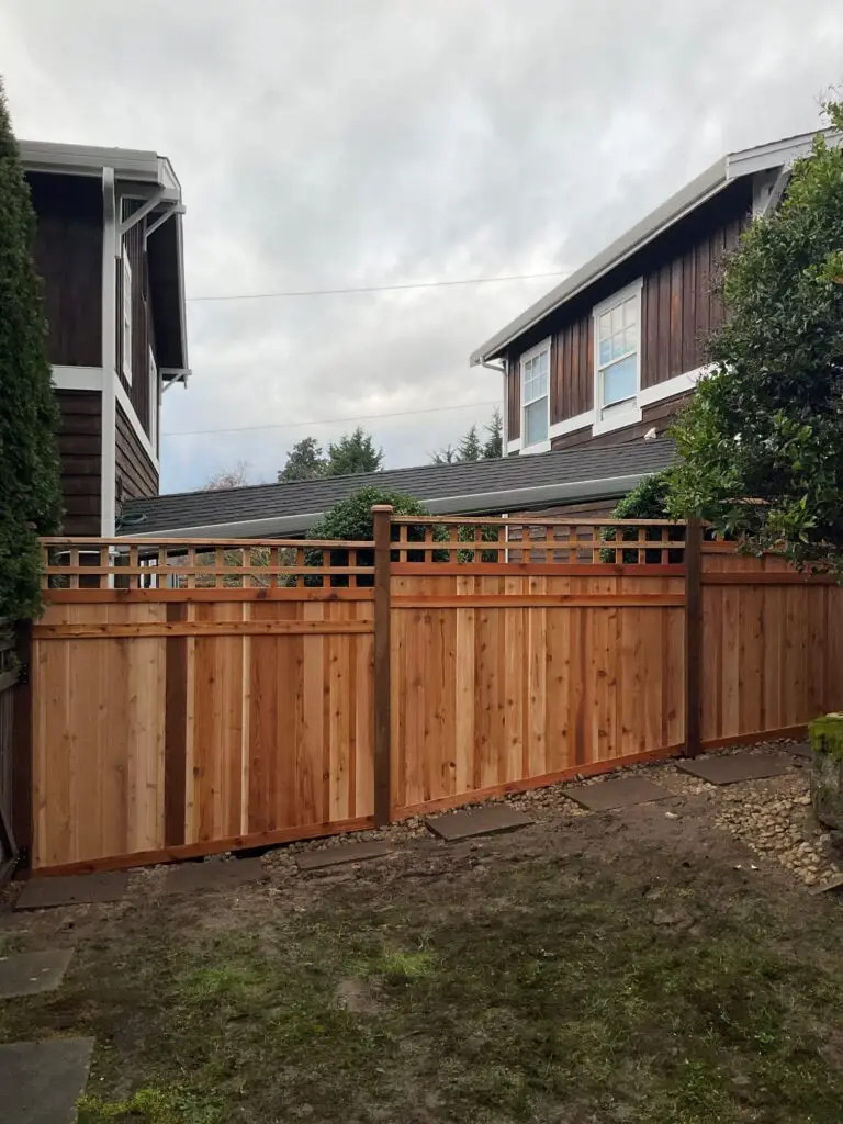 Close-up of a Full Panel with Decorative Lattice Fence Installation in Kirkland, with stone pavers on a gravel path and a house with white-trimmed windows in the background.