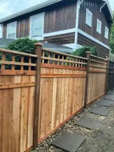 Wooden Full Panel with Decorative Lattice Fence Installation in Kirkland, featuring a pathway with stone pavers and a nearby house with dark wood siding.