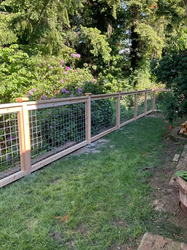 A completed hog wire fence installed in a backyard, showcasing the wooden frame and wire panels, illustrating hog wire fence cost considerations.