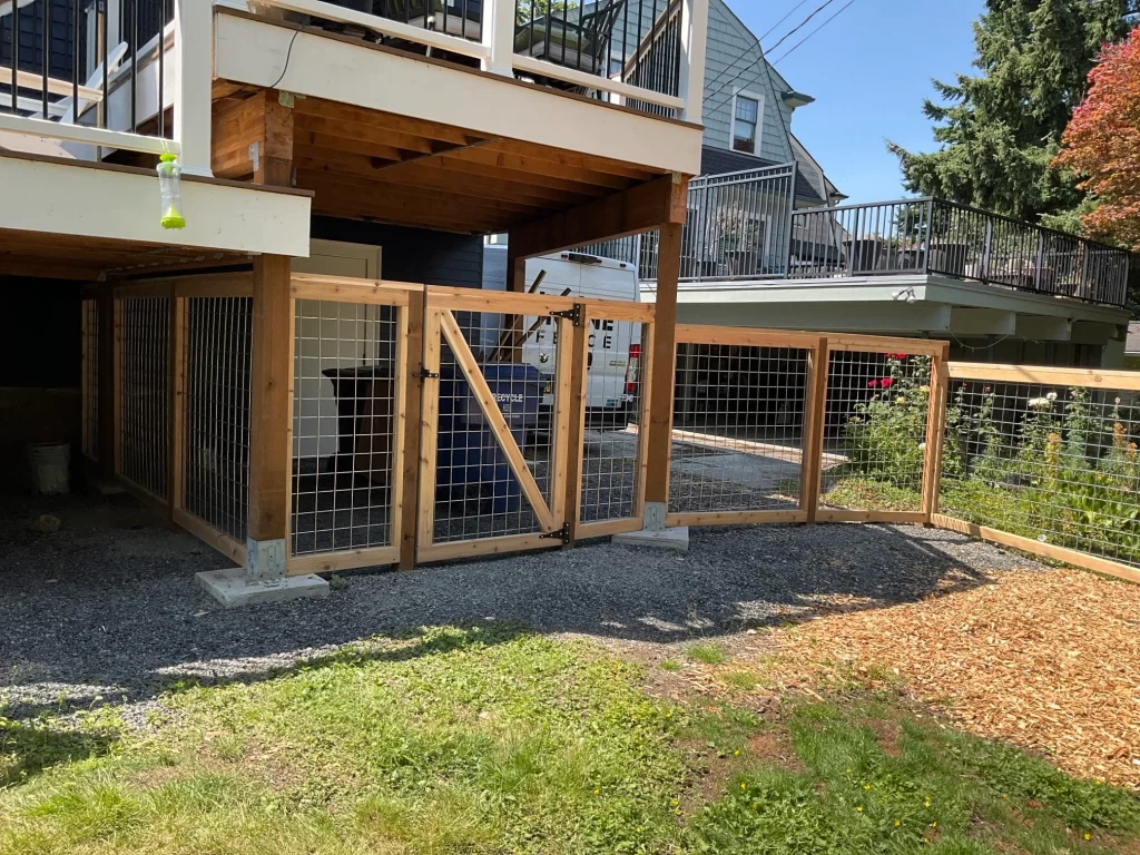 An under-deck area with a completed hog wire fence and gate, demonstrating material and installation choices, helping estimate hog wire fence cost.