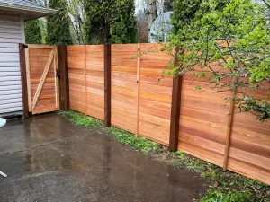 A beautiful horizontal cedar fence with a sturdy gate, featuring a mix of wood tones. For those considering this project, the horizontal cedar fence installation cost in Seattle can vary based on the materials and design chosen.