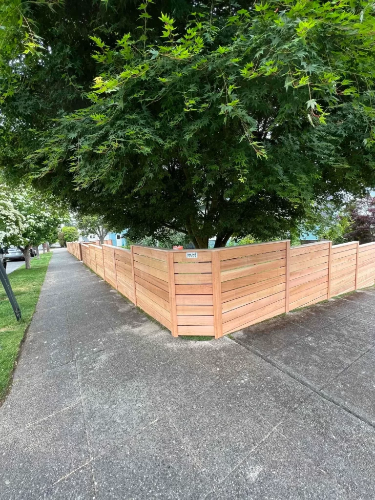 Horizontal wooden fences Seattle enclosing a corner yard with shade trees