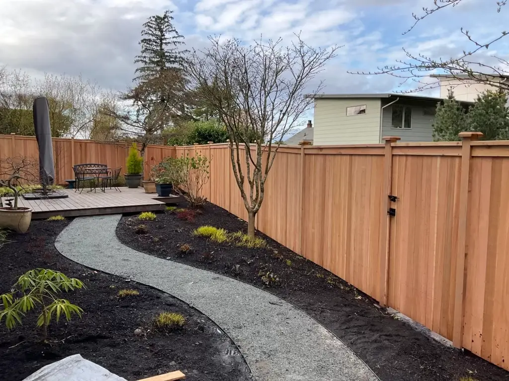 A well-maintained cedar fence surrounding a backyard with a pathway and deck in Seattle.