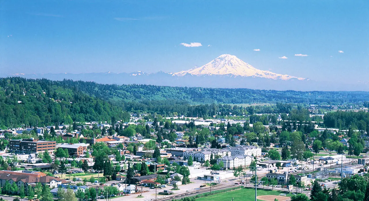 Kent, WA cityscape with Mount Rainier in the background under a clear blue sky.