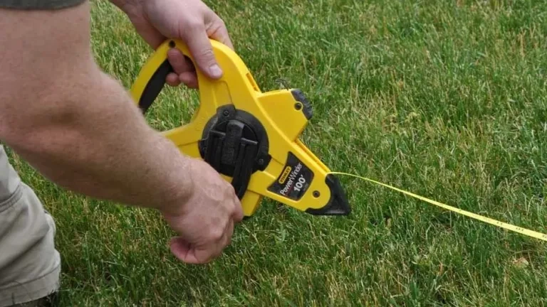 A person using a tape measure to ensure the fence meets horizontal fence height rules.