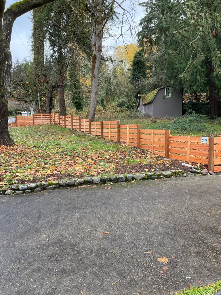 A low, modern horizontal wood fence lines a driveway in autumn, offering a different boundary solution than classic pergola walls.