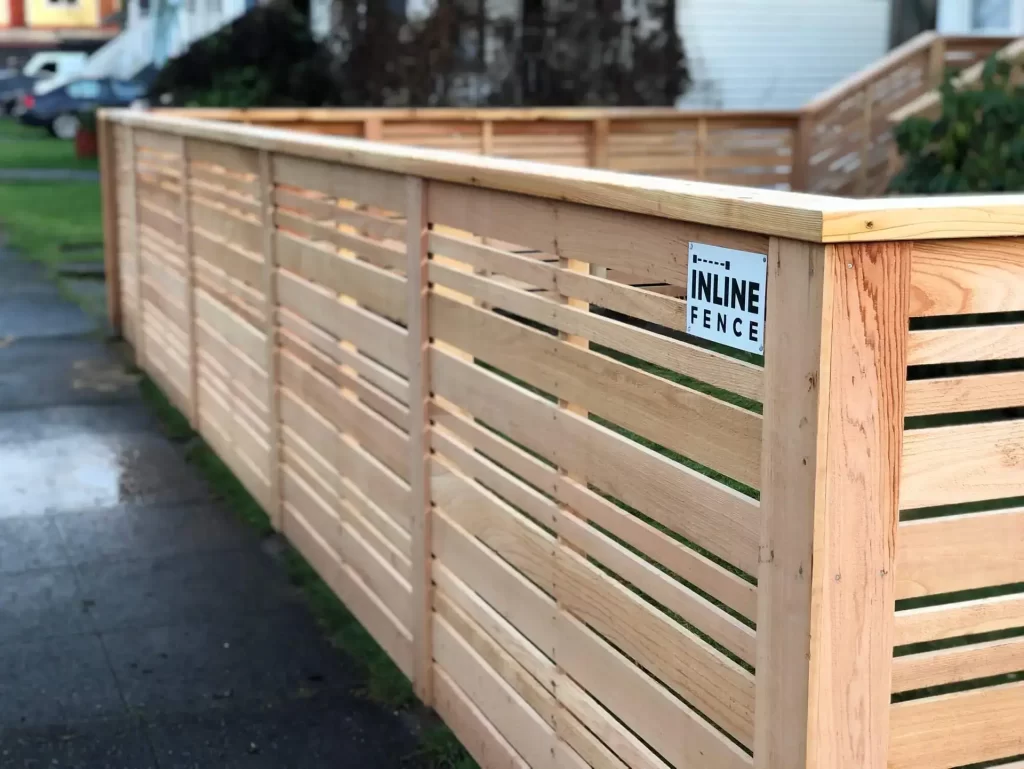 A contemporary cedar fence featuring horizontal slats and a small company sign. A great example from a quality North Bend fence builder.