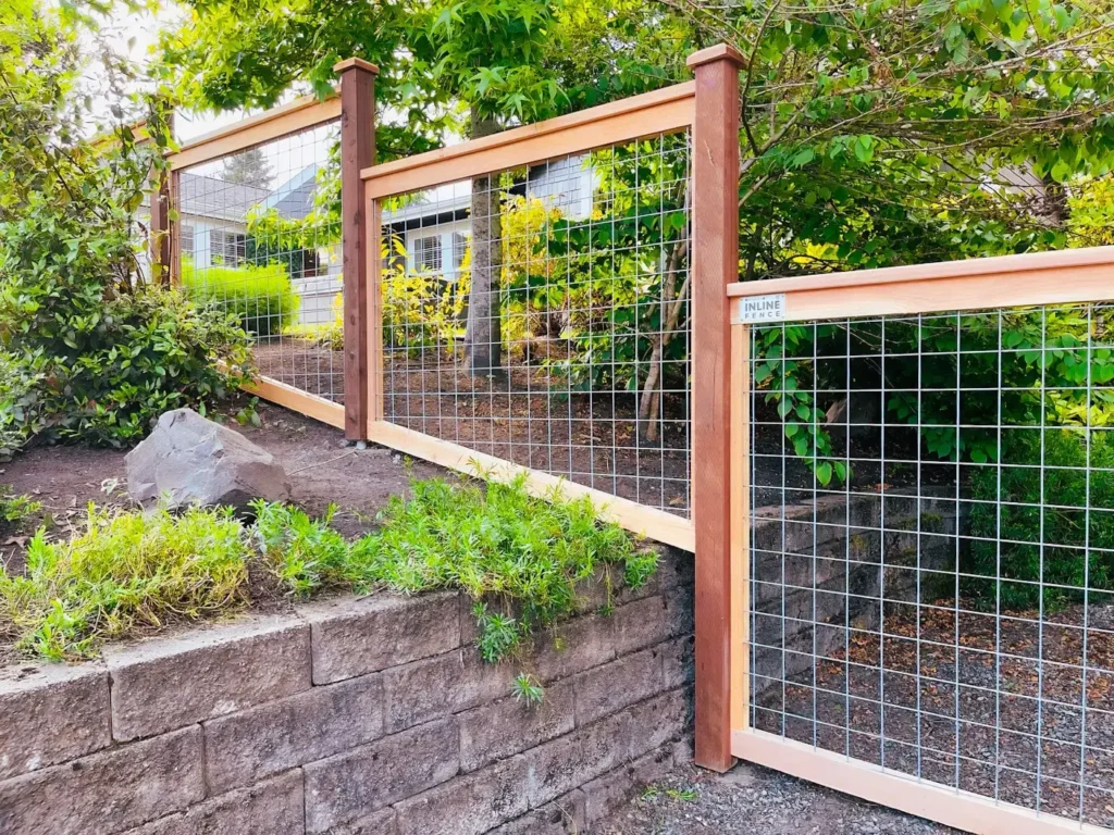 Hog wire fence on a retaining wall, showing a clean final installation and meeting diverse fencing needs with quality materials.