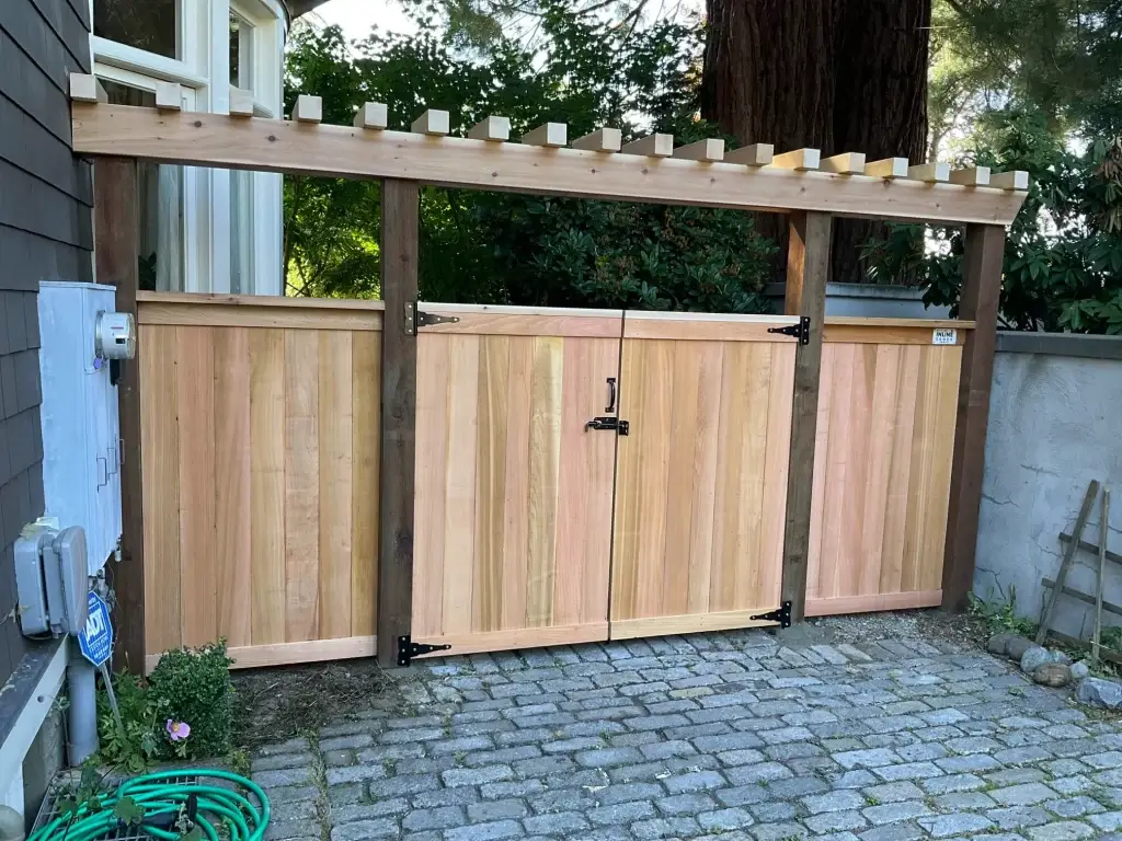 A pipe fence with wood panels and a pergola-style gate, enhancing privacy and style.