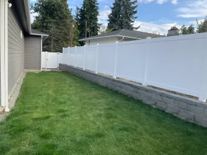 A clean white vinyl fence with a gate, bordering a well-maintained lawn, highlighting the vinyl fence cost in Seattle.