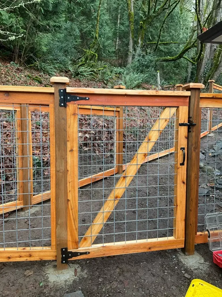 Wooden gate with a diagonal support and hog wire fence panels, perfect for backyard security.