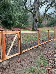 A wooden fence featuring strong hog wire panels, ideal for securing property in the Pacific Northwest.
